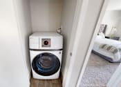 Thumbnail 6 of 83 - A white front load washing machine in a small room.