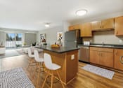 Thumbnail 3 of 32 - A kitchen with a black counter top and white chairs.