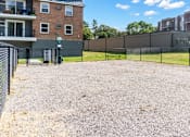 Thumbnail 34 of 34 - A gravel lot is surrounded by a fence and a brick building.