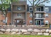 Thumbnail 2 of 34 - A modern apartment building with a stone wall in front.