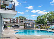 Thumbnail 23 of 34 - A swimming pool surrounded by lounge chairs and apartment buildings.