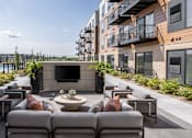 Thumbnail 49 of 61 - A patio with grey couches and a fireplace.