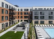 Thumbnail 51 of 61 - A modern building with a pool and lounge chairs.