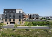 Thumbnail 61 of 61 - A modern building complex with a parking lot in front.