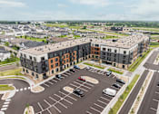 Thumbnail 60 of 61 - A large parking lot in front of a multi-story building.