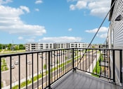 Thumbnail 38 of 61 - A balcony overlooks a parking lot and a road.