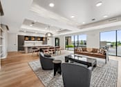 Thumbnail 9 of 61 - A modern living room with a dining area and a kitchen in the background.