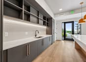 Thumbnail 13 of 61 - A modern kitchen with dark grey cabinets and a wooden floor.