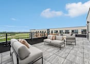 Thumbnail 15 of 61 - A balcony with two couches and a table.
