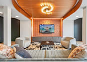 Thumbnail 4 of 61 - A living room with a wooden ceiling and a television mounted on the wall.