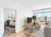 Thumbnail 40 of 61 - A modern living room with a grey sofa, a wooden coffee table, and a large window overlooking a cityscape.