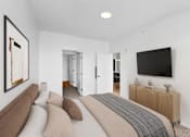 Thumbnail 41 of 61 - A modern bedroom with a large bed and a flat screen TV on the wall.
