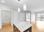 Thumbnail 18 of 47 - A spacious kitchen with a granite countertop and white cabinets.