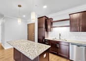 Thumbnail 12 of 47 - A kitchen with a granite countertop and wooden cabinets.