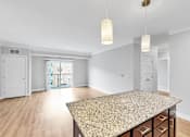 Thumbnail 13 of 47 - A spacious room with a granite countertop and wooden flooring.