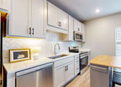 Thumbnail 59 of 67 - A modern kitchen with white cabinets and stainless steel appliances.