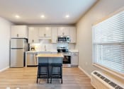Thumbnail 60 of 67 - A kitchen with a refrigerator, microwave, oven, and sink.