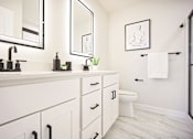 Thumbnail 8 of 15 - A bathroom with a white counter top and a white toilet.