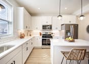 Thumbnail 1 of 15 - A modern kitchen with white cabinets and a large island.