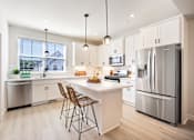 Thumbnail 2 of 15 - A modern kitchen with a white island and stainless steel appliances.
