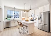 Thumbnail 1 of 48 - a white kitchen with stainless steel appliances and a white island with two stools at Foxtail Hollow Townhomes, Minnesota