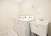 Thumbnail 14 of 15 - A white washing machine and sink in a small laundry room.