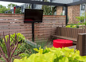 Thumbnail 6 of 40 - a patio with a tv and a bench in front of a brick building