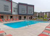 Thumbnail 3 of 40 - a swimming pool with chaise lounge chairs and a building in the background