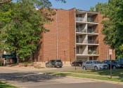 Thumbnail 36 of 38 - a large brick apartment building with cars parked in front