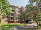 Thumbnail 38 of 38 - a large brick apartment building with trees and a pathway