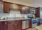 Thumbnail 30 of 82 - a kitchen with dark wood cabinets and granite countertops at Lake Jonathan Flats, Chaska, MN