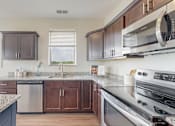 Thumbnail 2 of 82 - A kitchen with a granite countertop and stainless steel appliances. at Lake Jonathan Flats, Chaska, Minnesota