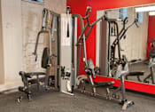 Thumbnail 34 of 55 - A gym with a variety of equipment including a leg press machine and a chest press machine.