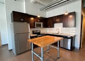 Thumbnail 36 of 44 - A kitchen with a table and stainless steel appliances.at Gurley Lofts, Minneapolis, MN 55401