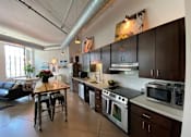 Thumbnail 9 of 44 - A kitchen with a black stove top oven and a black microwave.at Gurley Lofts, Minnesota, 55401