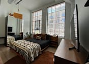 Thumbnail 13 of 44 - A bedroom with a bed, a couch, a television, and a window with blinds.at Gurley Lofts, Minnesota