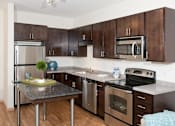 Thumbnail 36 of 73 - A kitchen with brown cabinets and stainless steel appliances.at Third North Apartments, Minneapolis, MN