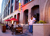 Thumbnail 69 of 73 - A man in a white shirt is standing outside a restaurant with a red umbrella.at Third North Apartments, Minnesota