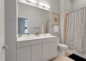 Thumbnail 12 of 77 - A bathroom with a white toilet, sink, and striped shower curtain.at Viridium Apartments, Minnesota, 55401
