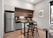 Thumbnail 15 of 77 - A kitchen with a refrigerator, stove, and bar stools.at Viridium Apartments, Minnesota, 55401