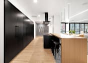 Thumbnail 21 of 77 - A modern kitchen with black cabinets and a wooden island.at Viridium Apartments, Minneapolis 