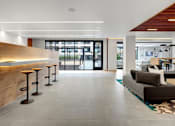 Thumbnail 25 of 77 - A modern living room with a couch, a table, and a bar with stools.at Viridium Apartments, Minneapolis 