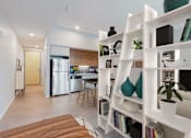 Thumbnail 59 of 77 - A modern kitchen with a refrigerator, a dining table, and a bookshelf.at Viridium Apartments, Minneapolis, MN 