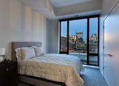 Thumbnail 75 of 77 - A bedroom with a large bed and a view of the city.at Viridium Apartments, Minnesota 