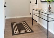 Thumbnail 24 of 80 - A hallway with a black and white rug on the floor at The Barnum Apartments, White Bear Lake, Minnesota