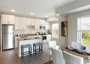 Thumbnail 27 of 80 - A modern kitchen with white cabinets and a glass table at The Barnum Apartments, Minnesota