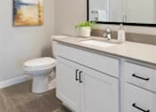 Thumbnail 36 of 80 - A bathroom with a toilet, sink, and a mirror at The Barnum Apartments, Minnesota