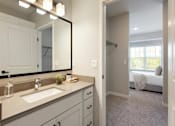 Thumbnail 39 of 80 - A bathroom with a sink, mirror, and a bedroom in the background at The Barnum Apartments, White Bear Lake, MN,  55110