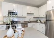 Thumbnail 41 of 80 - A kitchen with white cabinets and a tray with a vase and dishes on it at The Barnum Apartments, White Bear Lake, Minnesota
