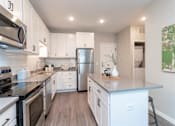 Thumbnail 43 of 80 - A modern kitchen with stainless steel appliances and white cabinets at The Barnum Apartments, White Bear Lake